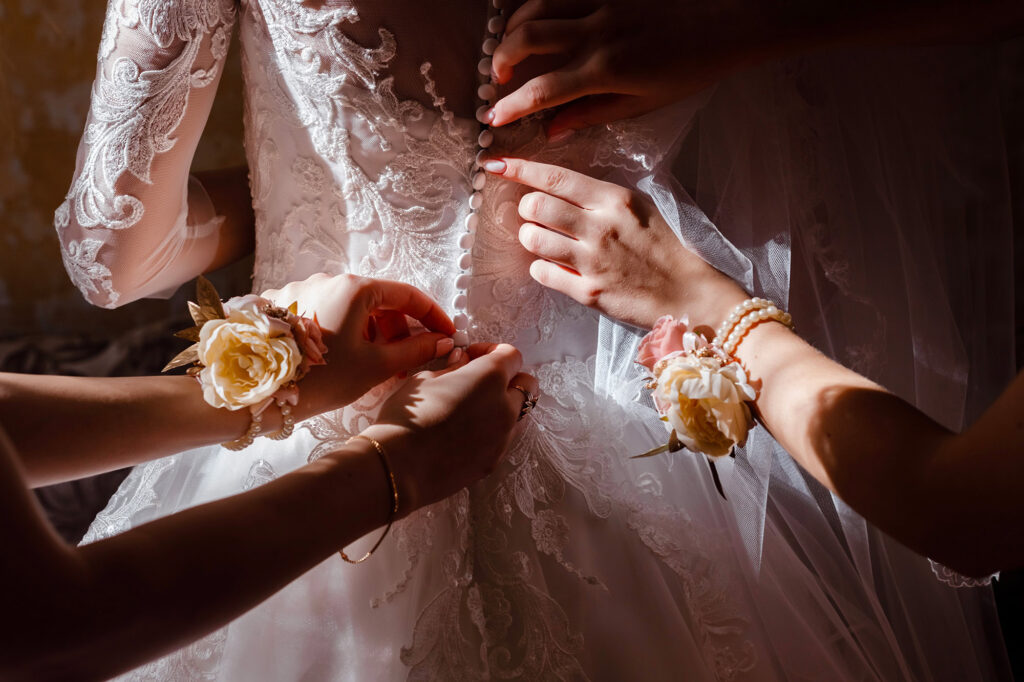 Proches aidant une mariée à fermer sa robe pendant la préparation du jour J