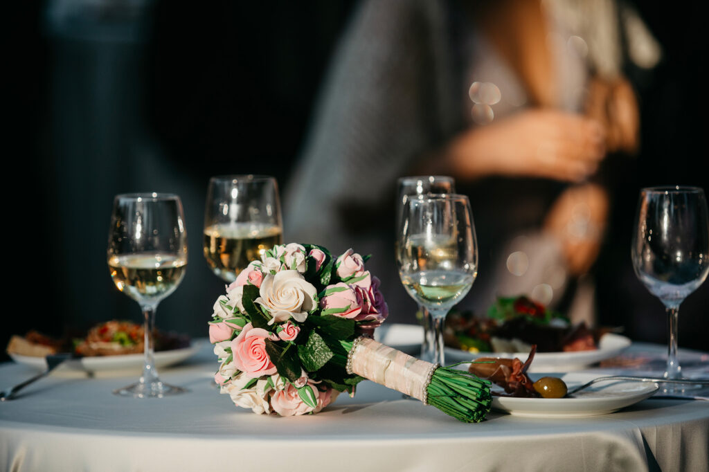 Table dressée avec bouquets de roses, bougies et verres pour une réception de mariage