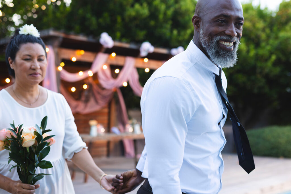 Couple interculturel souriant après une cérémonie extérieure