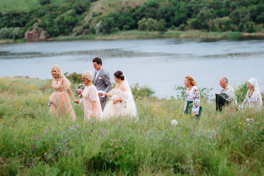 Cortège de mariage avançant dans un champ près d'un lac