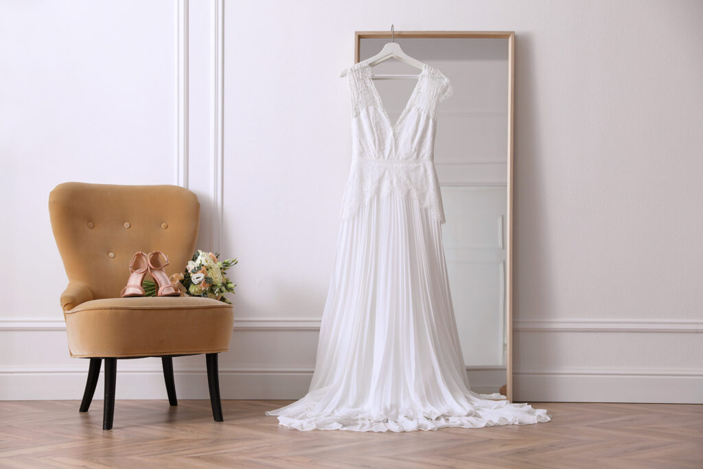 Robe de mariée blanche suspendue dans une chambre avant les essayages
