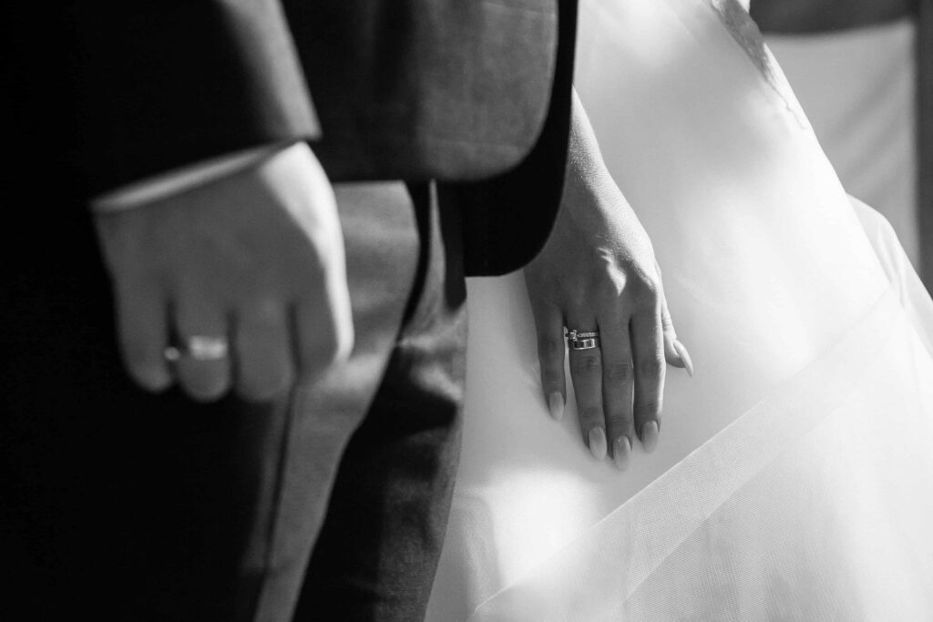 Photographie en noir et blanc des mains et de la robe d'une mariée